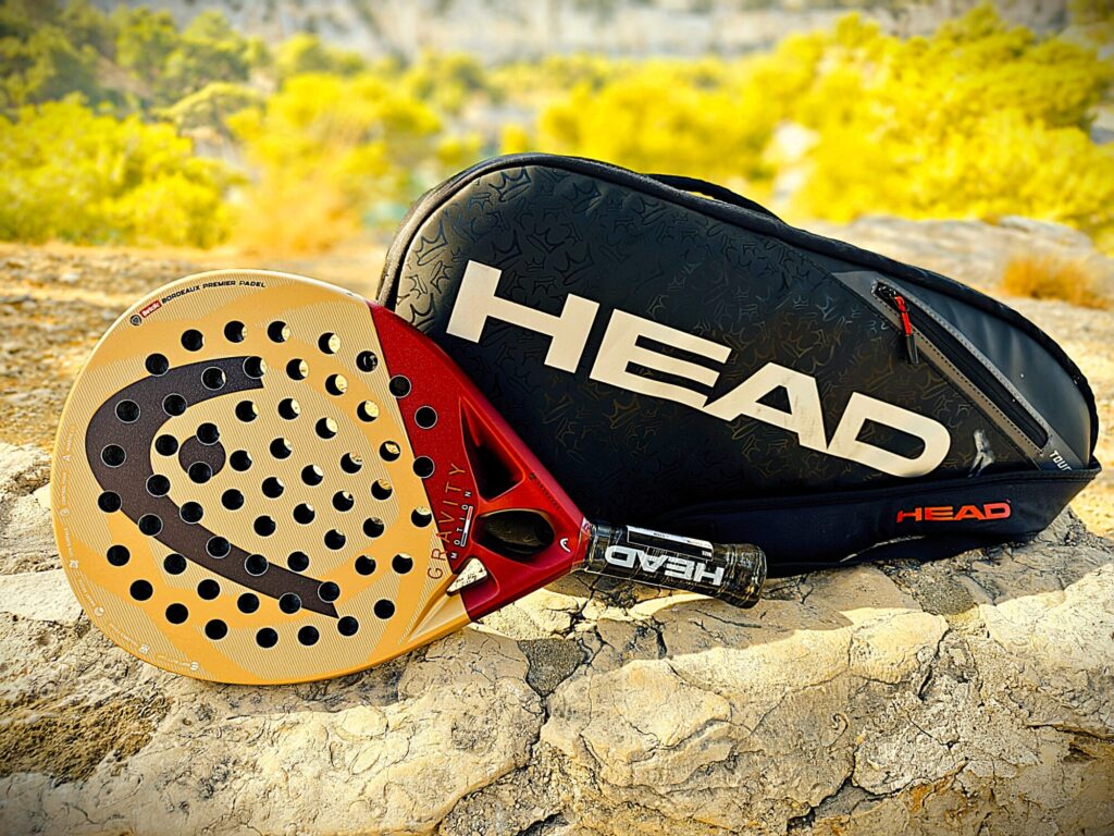 Wakeboard and bag resting on a sunlit rocky surface outdoors.