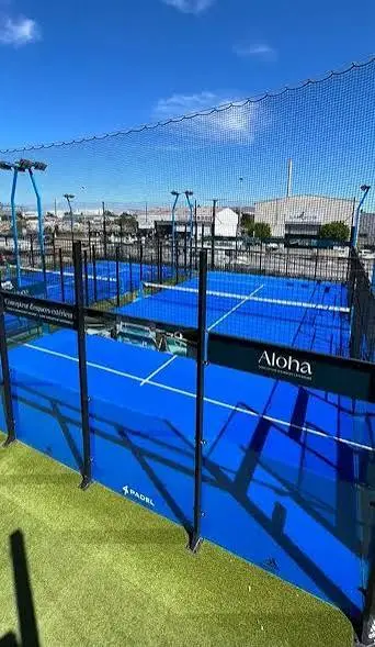 高手 Padel 2俱乐部| Padel Magazine 室外板式网球场,亮蓝色的场地,黑色网状围栏和网状边界,在湛蓝的天空下。