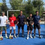 Bernard et Rubio confirment leur statut et soffrent le titre au P1000 Sud Padel Bel Air | Padel Magazine Six men pose with rackets and trophies on a bright blue padel court after a match, drinks lined up in front, a banner nearby.