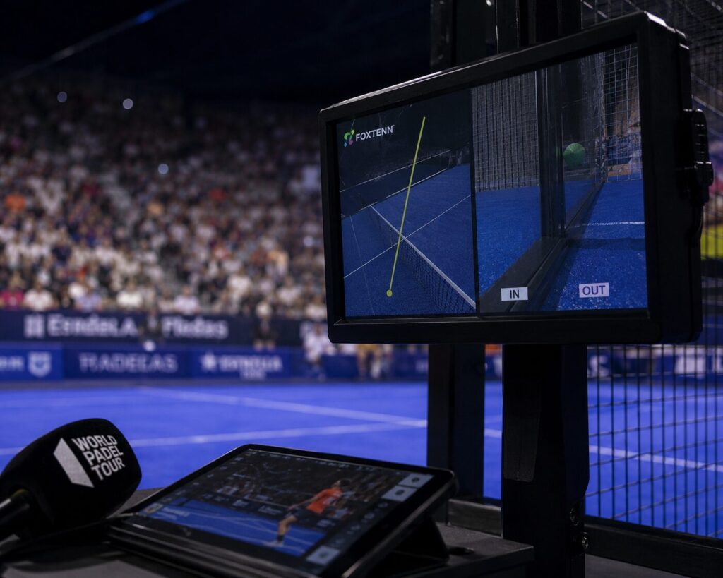 ChatGPT Image 4 juil 2026 13_18_57 | Padel Magazine Broadcast booth monitor showing a padel court with IN and OUT markers; microphone labeled World Padel Tour and a tablet in the foreground.