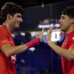 Coello chambre Tapia avant la finale de la coupe du monde et lEspagne lui donne raison | Padel Magazine Two male athletes in red jerseys high-fiving in a dimly lit sports arena.