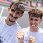 FIP Promises Paris by WME Sports - Ils se sont fait très peur mais Robert et Guy de Chamisso sont champions en U18 | Padel Magazine Two young men in white shirts smile at the camera, posing with fists raised in a friendly selfie on an outdoor sports court.