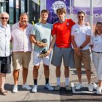 P1000 Reichstett Wagner et Couturier confirment leur statut et soffrent le titre | Padel Magazine Eight people pose together on a sunny tennis court after a trophy ceremony, two men holding wooden trophies.
