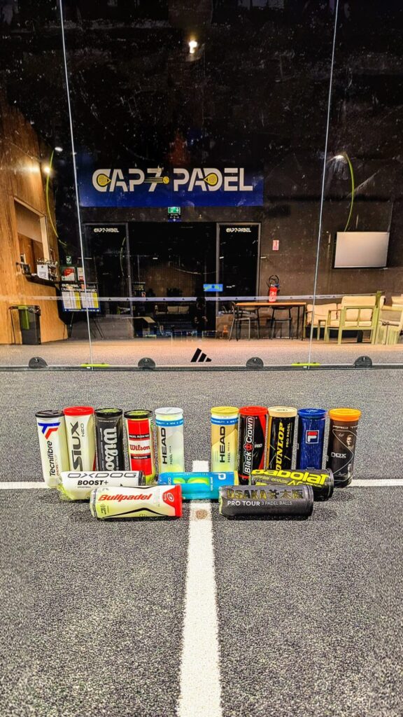 Polyvalentes | Padel Magazine Row of branded padel balls lined up on a counter inside a club, with a CAPPADEL sign visible on a glass wall in the background
