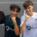 perrot huard de la marre | Padel Magazine Two young men on a padel court pose with fists up, holding rackets, wearing My Center Academy shirts and smiling at the camera.