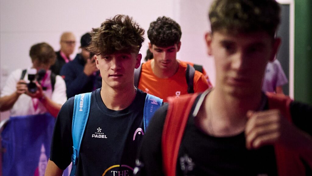 Curro Cabeza, 18 ans et déjà 49e mondial : le « Roi Arthur » n’a qu’à bien se tenir | Padel Magazine Teenagers walking in a hallway with backpacks; two are in focus at the front, one wearing a blue backpack and the other in an orange shirt behind him.