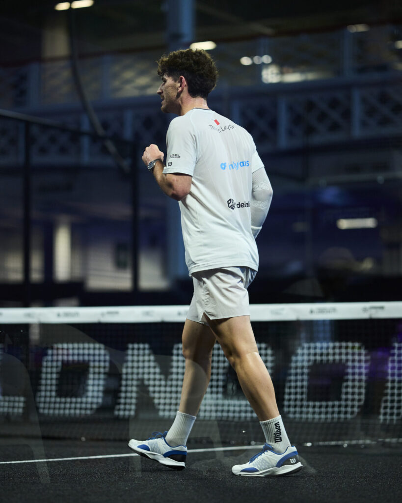 Leygue / Geens renversent Cepero / Torre : un exploit majuscule qui envoie un message fort | Padel Magazine Side view of a male athlete in white sportswear walking on an indoor court, net in the background.