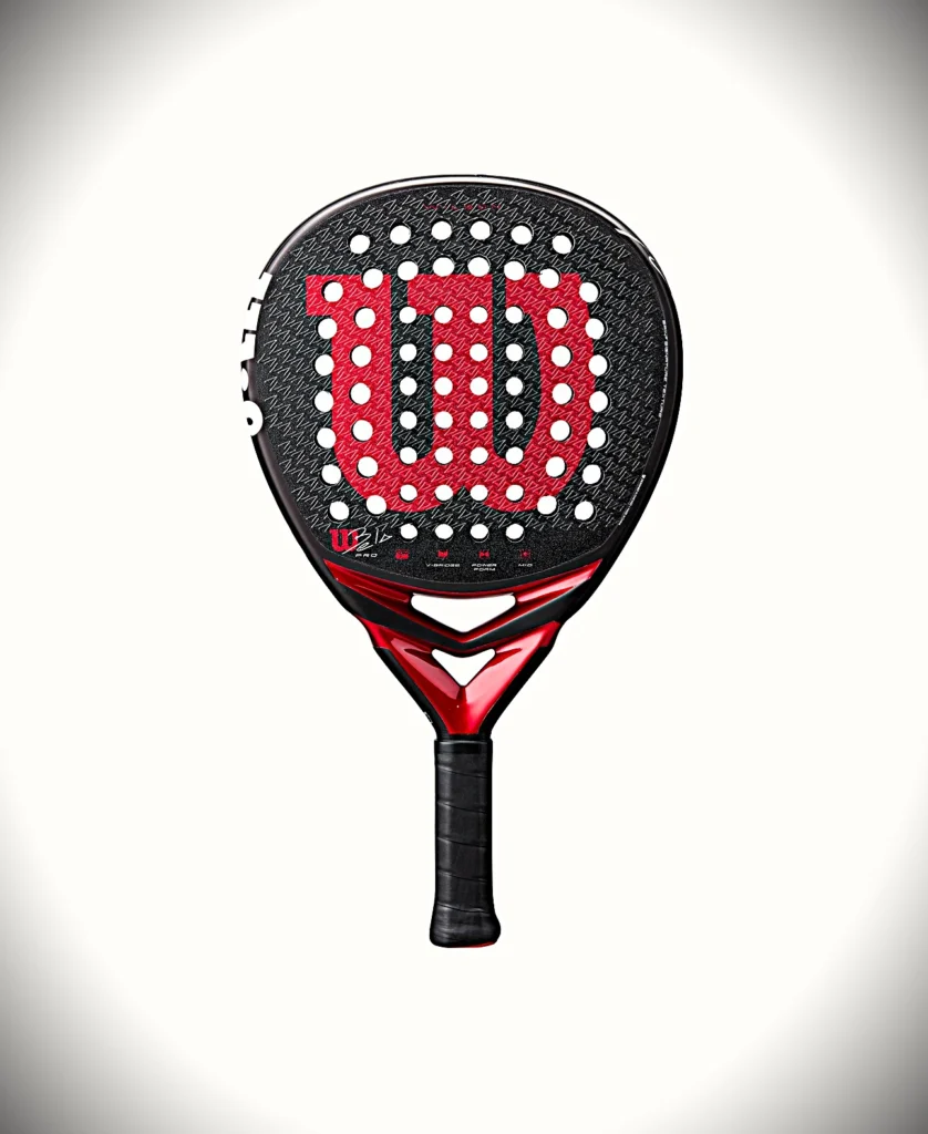 Padel Racchetta con superficie nera testurizzata, motivo a emblema rosso, numerosi fori bianchi e impugnatura rossa e nera nella parte inferiore.