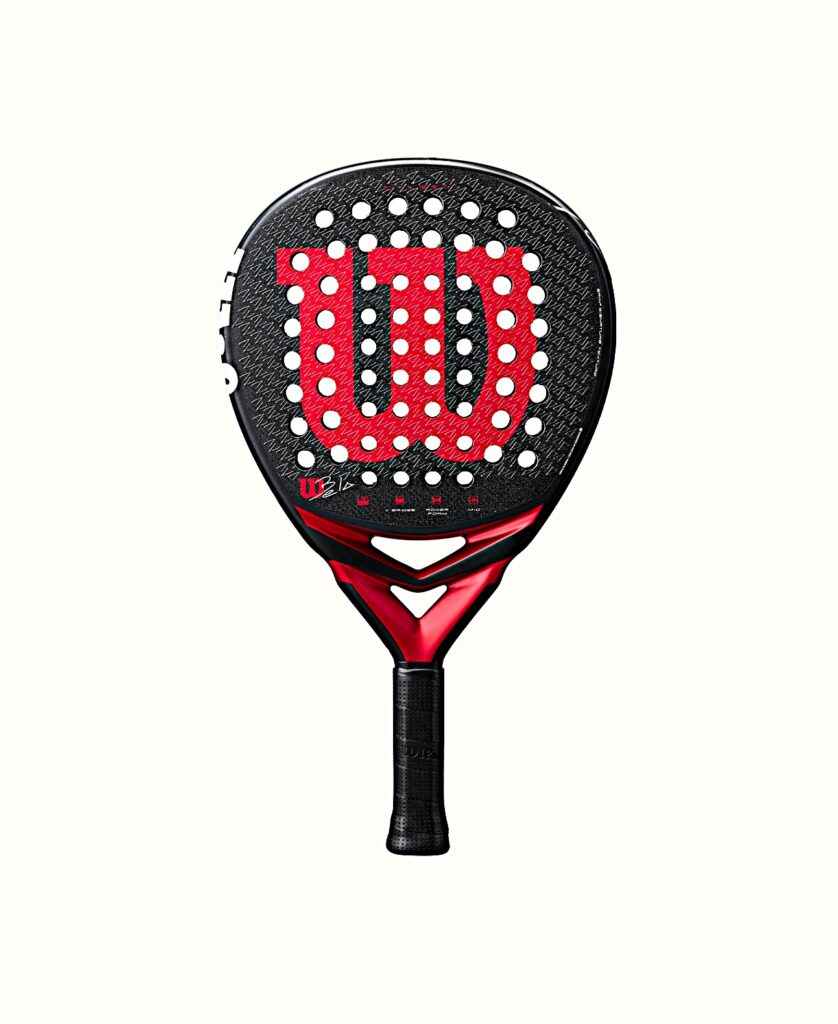 Bela V3 | Padel Magazine Padel racket with a black perforated face featuring a large red W logo, against a pale background.