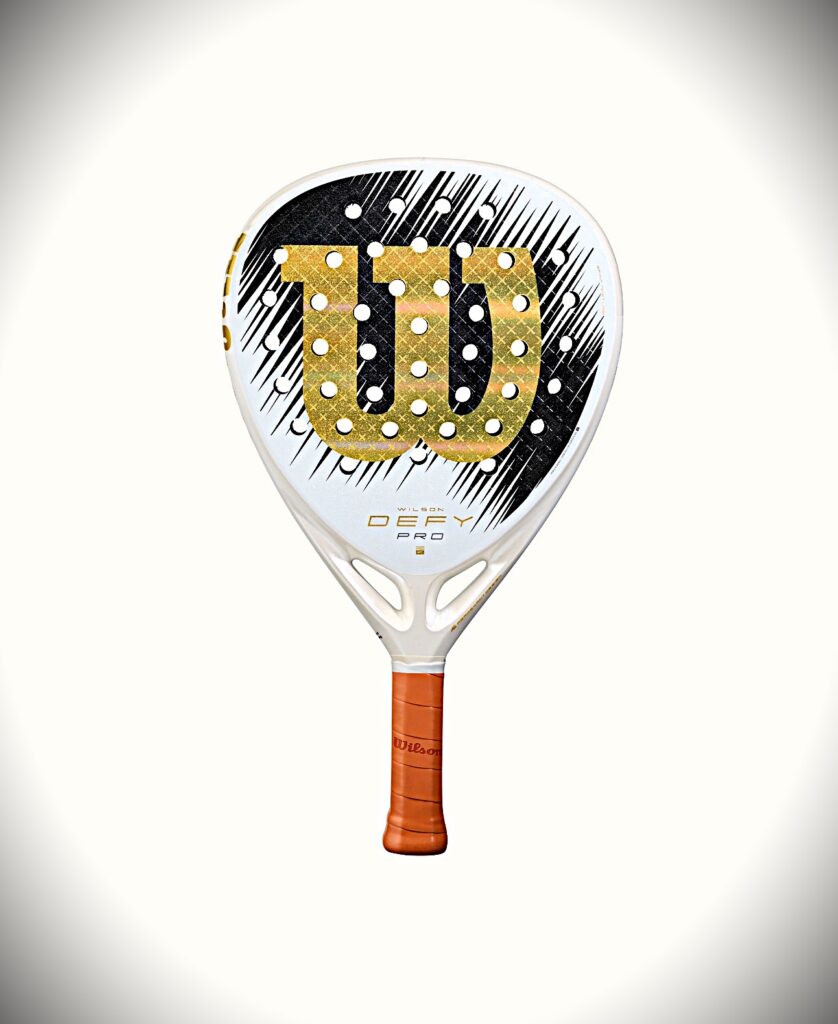 White Wilson padel racket with a gold number 7 logo, black striped background, and orange grip handle.