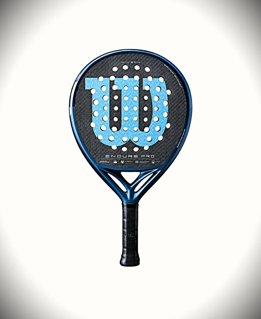 Endure V1 Pro | Padel Magazine 明るい背景に置かれた、円形のストリング穴のある青いウィルソン・エンデュア・プロのテニスラケットヘッドのクローズアップ。