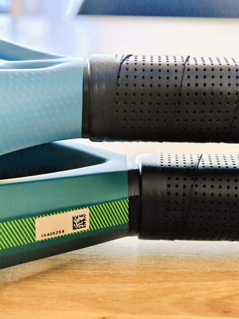 oplus_2105376 | Padel Magazine Close-up of a black perforated grip on a teal tool body with a barcode label reading 15405254.