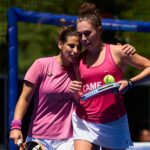Rodriguez_Dal Pozzo | Padel Magazine Two female tennis players in pink shirts celebrate together on a court, one holding a racket with a tennis ball tucked on the strings in celebration moment.