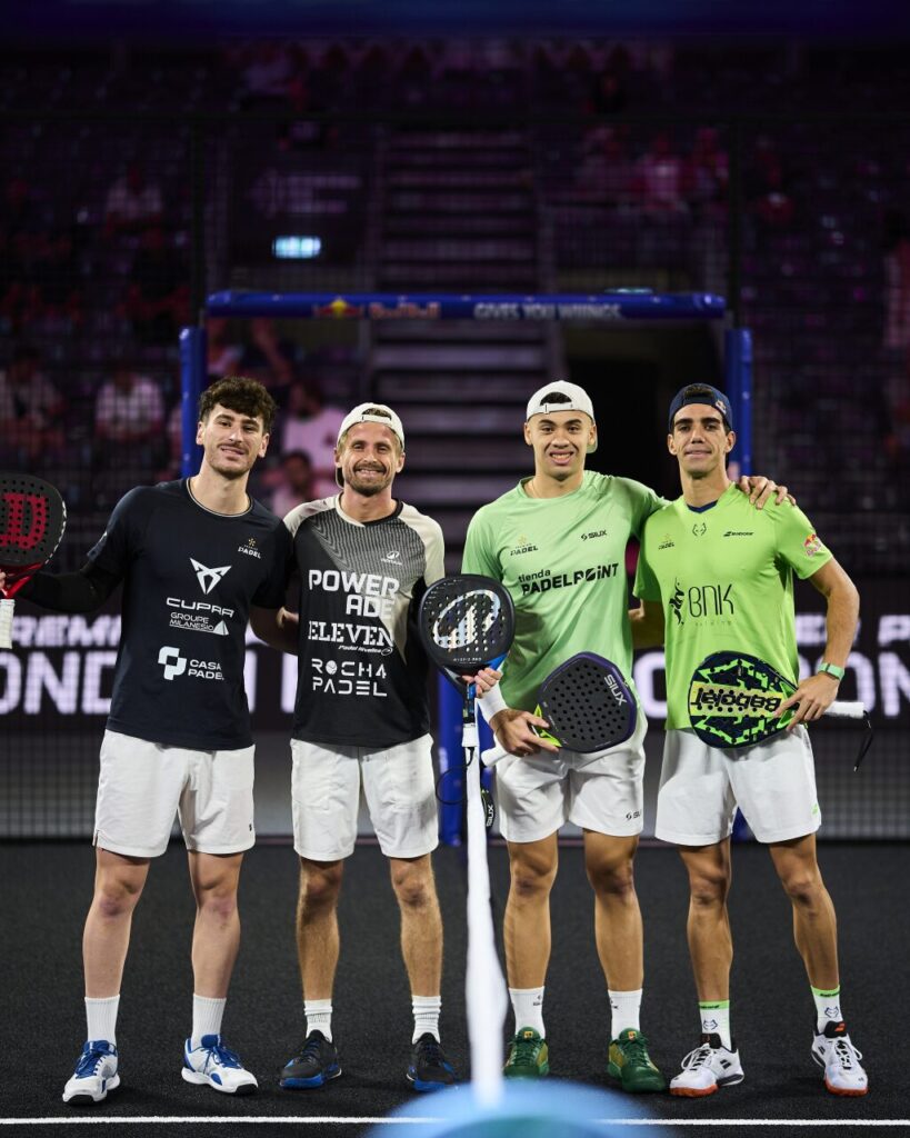 image | Padel Magazine Four male padel players posing together on a court, holding paddles, smiling after a match.