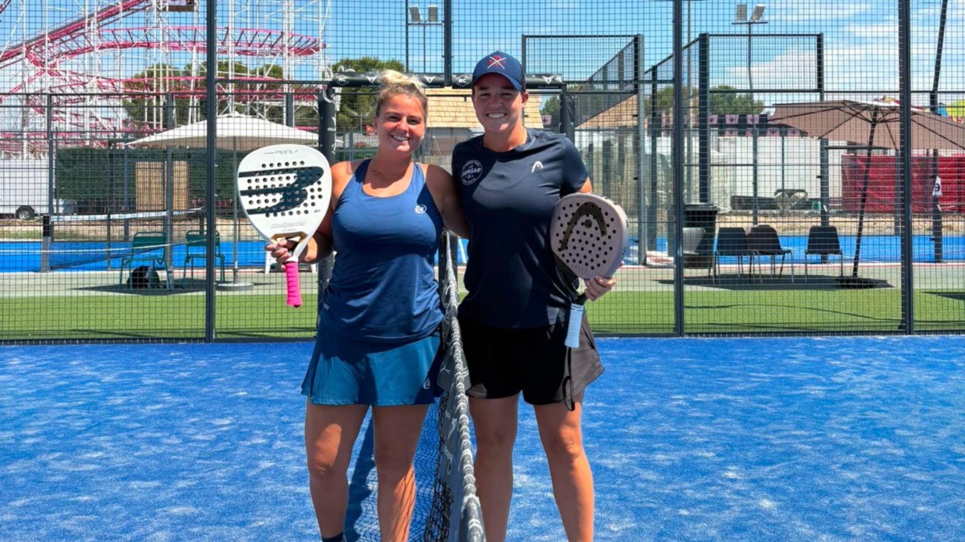 maligo bognard vainqueurs p1000 my center palavas | Padel Magazine Two women stand at a net on a blue padel court, smiling and holding paddles after a game outdoors.