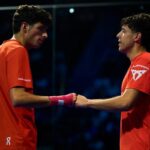 Tapia et Coello arrêtés à 27 : une série historique qui redéfinit le padel moderne | Padel Magazine Two male athletes in orange jerseys shake hands on an indoor court after a match.