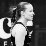 Side profile of a female athlete with a braided ponytail wearing a black tank top at a competition, in black-and-white.