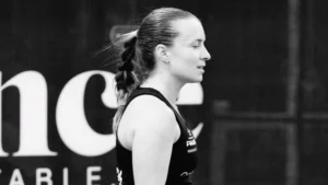Side profile of a female athlete with a braided ponytail wearing a black tank top at a competition, in black-and-white.